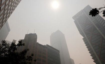 Sun shining through smoke onto high-rise buildings. Adobe